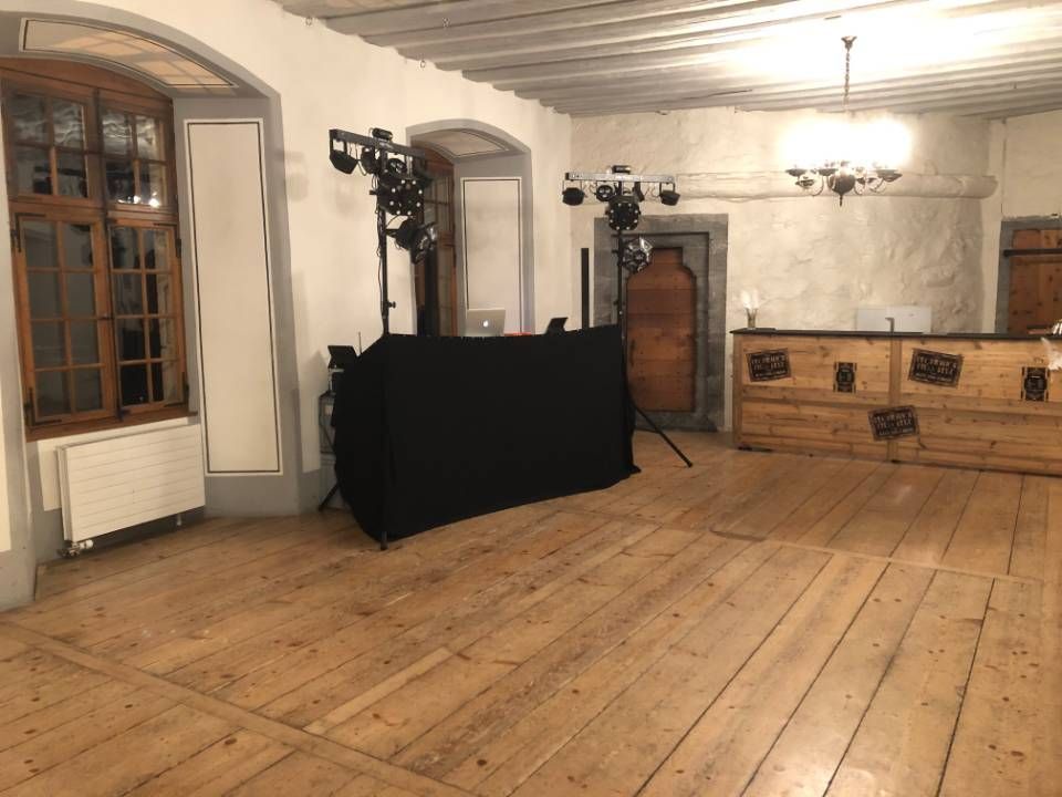 Pièce vide avec parquet, murs blancs et matériel de scène noir contre le mur du fond.