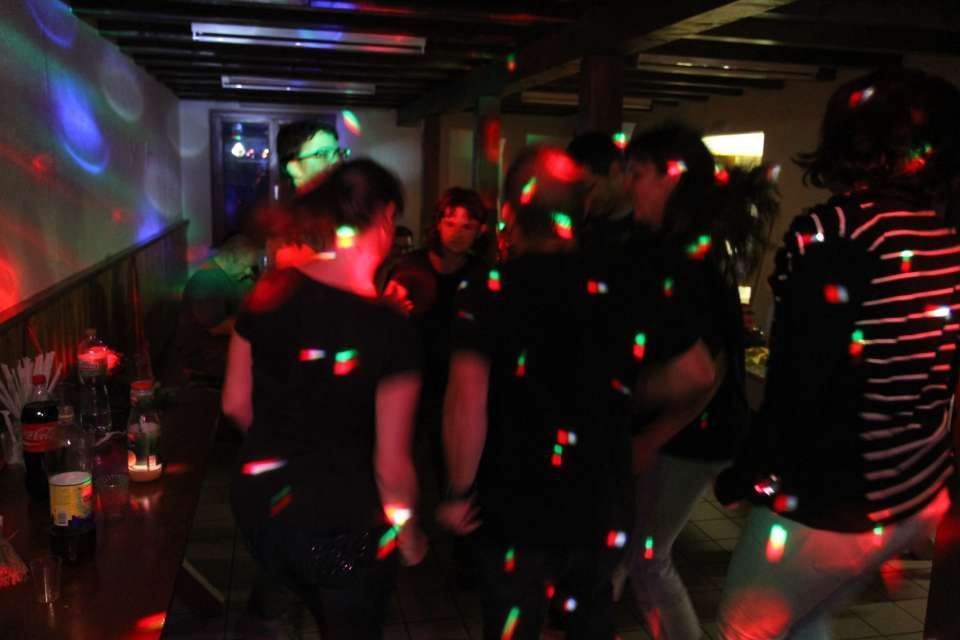 Des gens qui dansent dans une boîte de nuit plongée dans l'obscurité, illuminée par des lasers colorés.