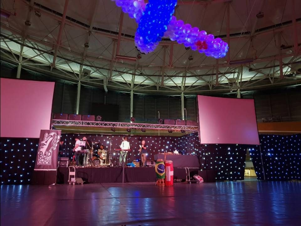 Scène vide avec écrans roses, lumières bleues au plafond et fond étoilé sombre dans une grande salle intérieure