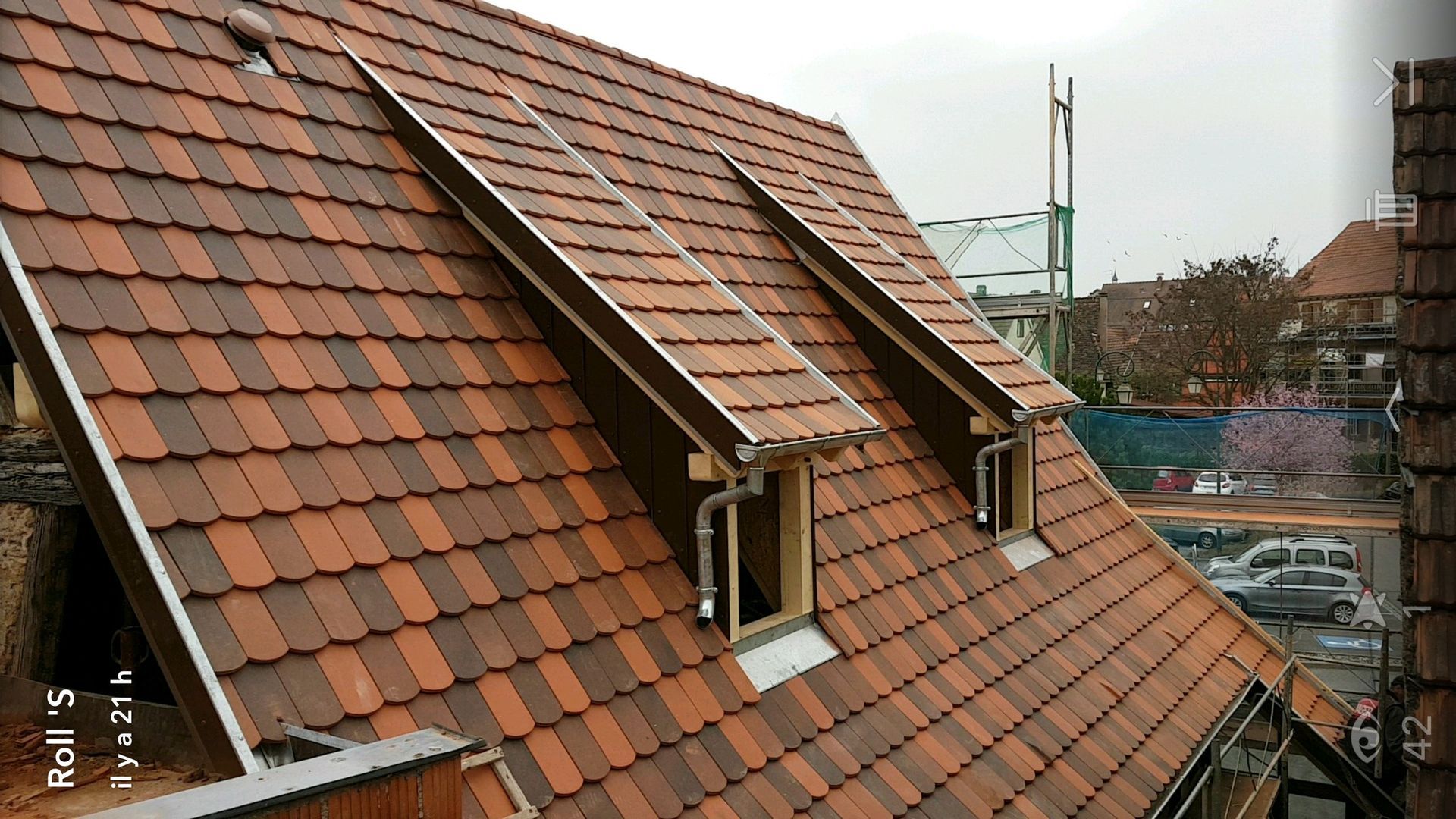 Toit de tuiles rouges avec trois lucarnes rectangulaires.