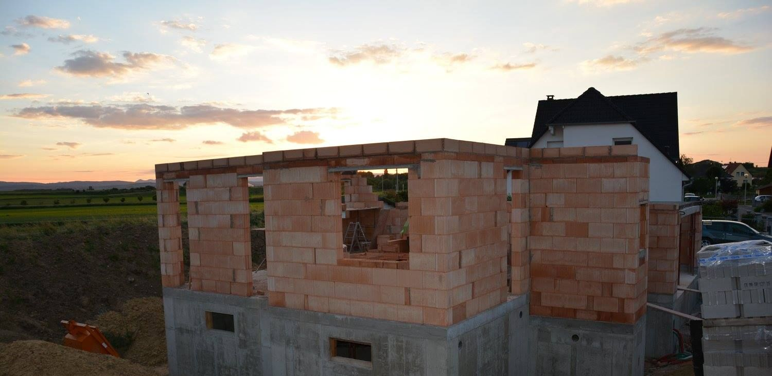 Construction d'une structure en briques dans un cadre rural au coucher du soleil.