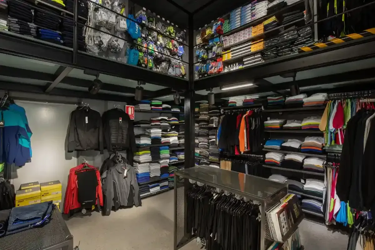 Vestidor con estantes y percheros repletos de ropa doblada, chaquetas y prendas colgadas en colores oscuros y brillantes.