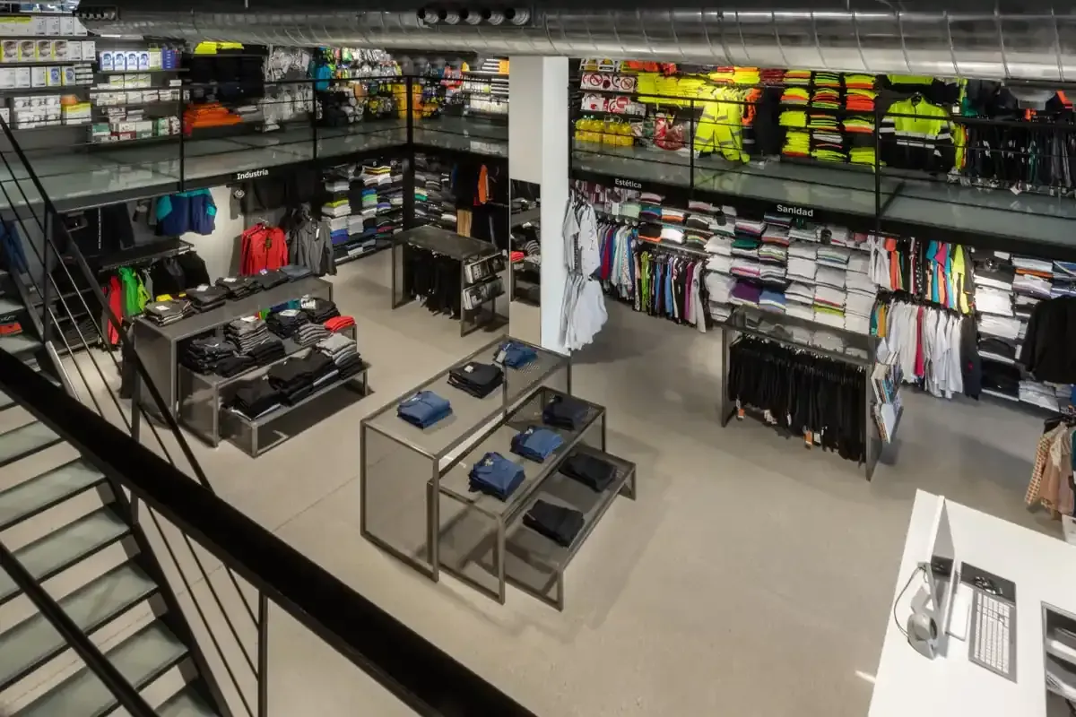 Interior de una tienda de artículos de pesca deportiva con estantes llenos de aparejos y mesas de exposición.