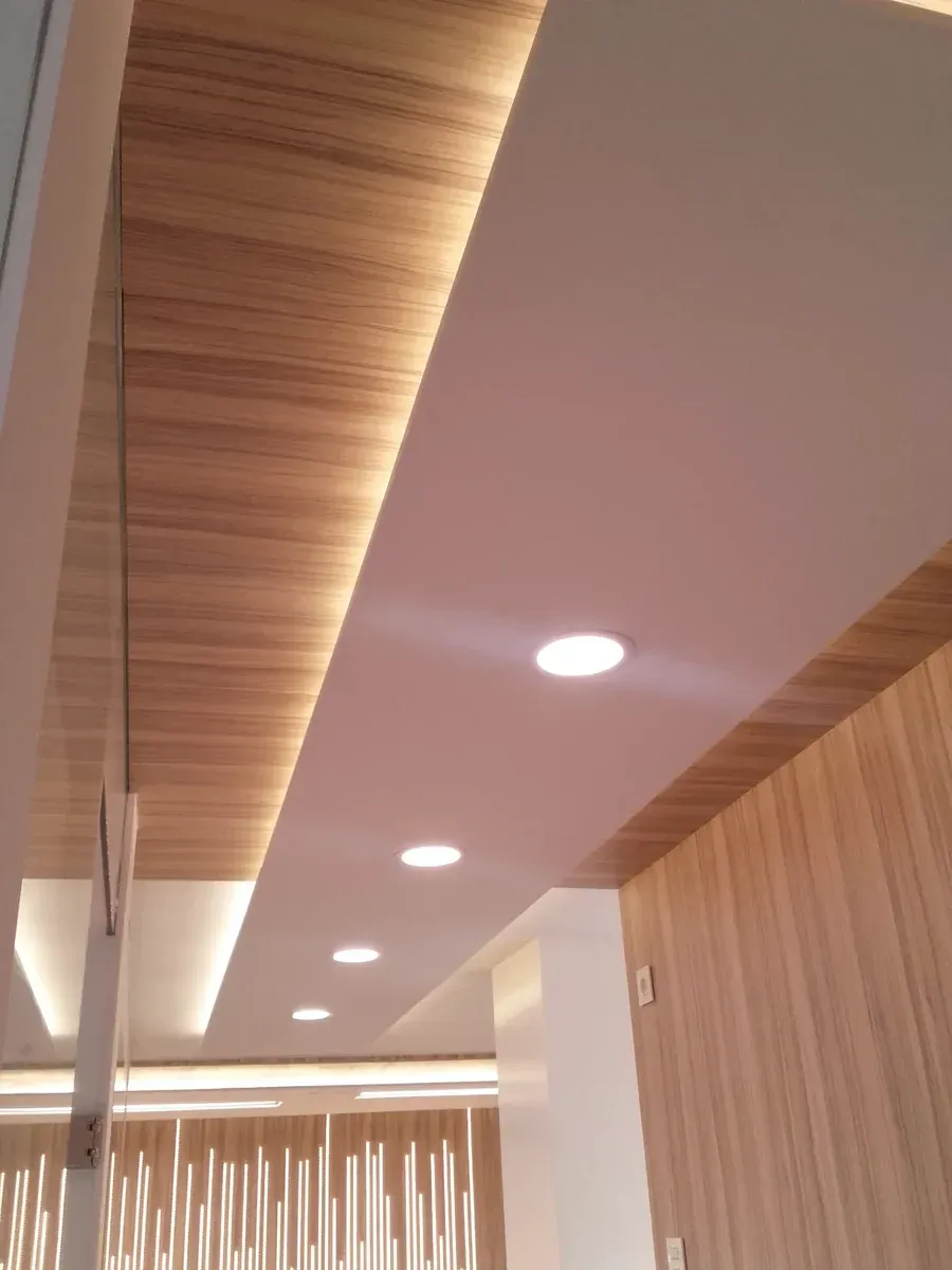 Techo moderno en el pasillo con luces empotradas, detalles de listones de madera y paredes blancas.