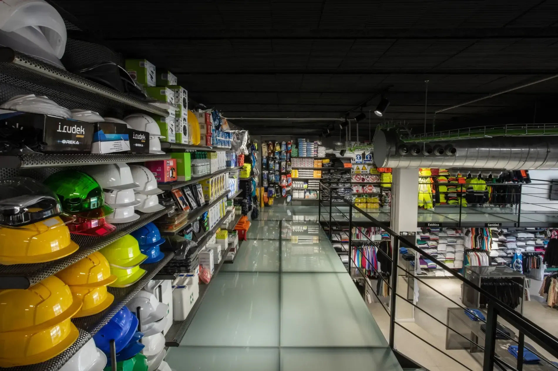 Un pasillo de una tienda minorista con coloridos cascos de seguridad y equipos en estantes de metal.