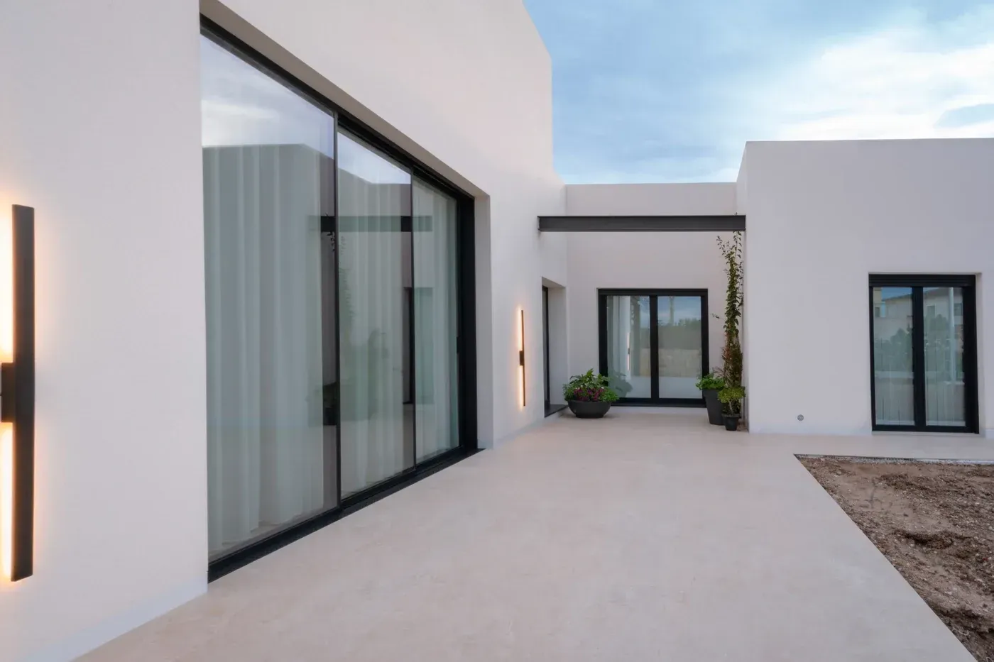 Patio blanco moderno con grandes puertas corredizas de vidrio y un camino pavimentado.