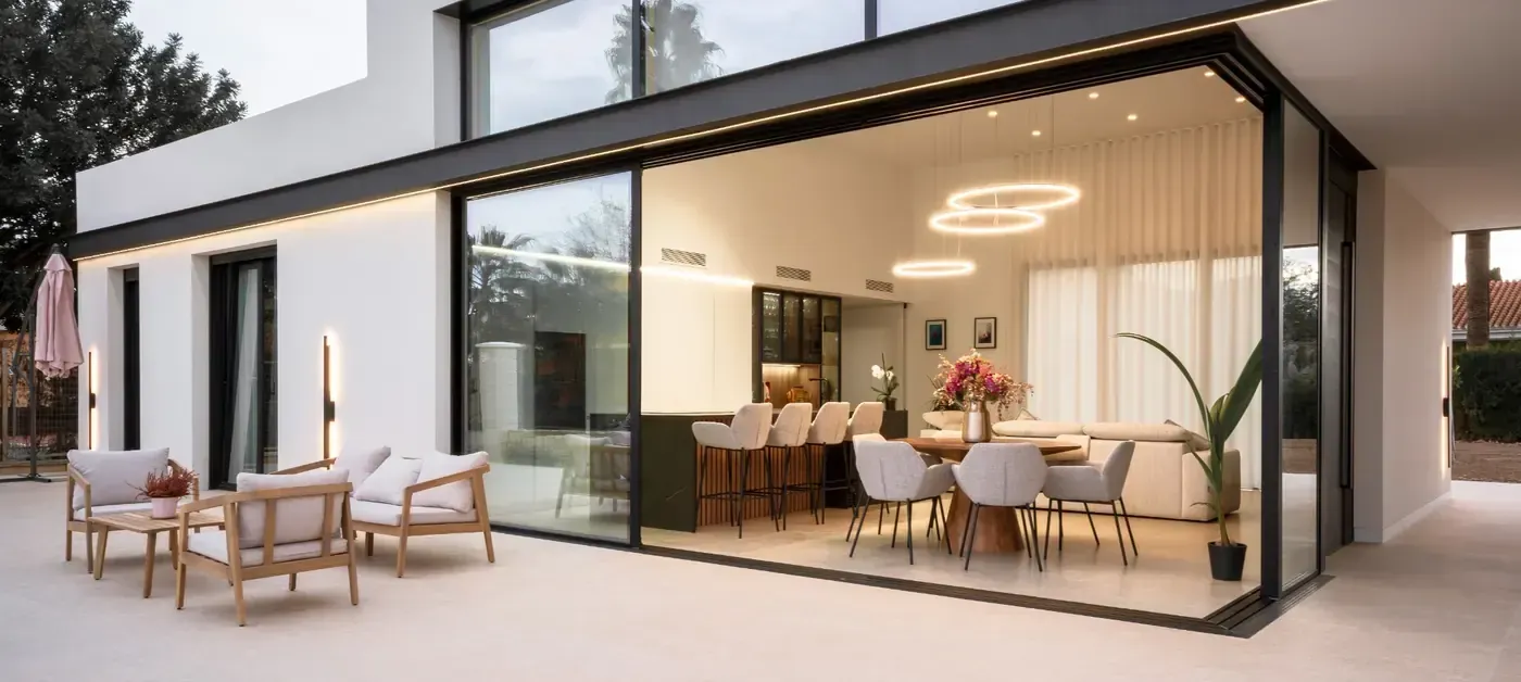 Casa moderna con fachada de cristal, un elegante salón-comedor diáfano y zona de estar en el patio