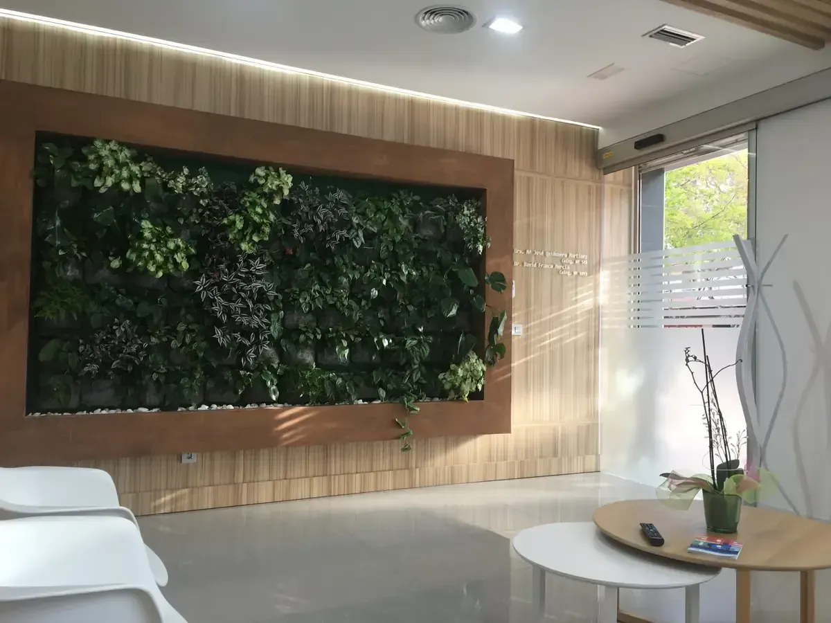 Vestíbulo moderno con una gran pared de plantas verdes enmarcadas