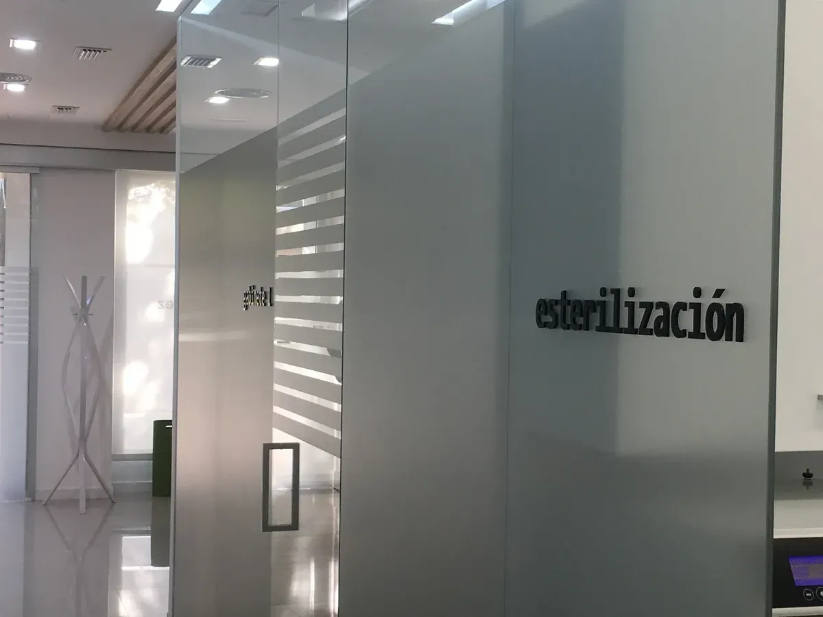 Pasillo de oficina moderno con puertas de cristal y la palabra “estilización” en un panel esmerilado.