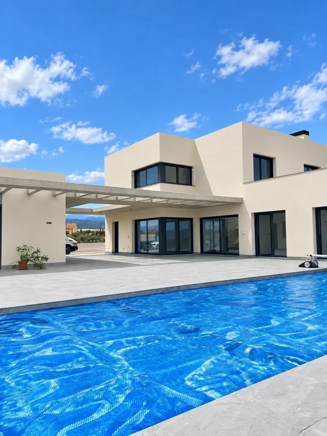 Casa blanca moderna con una piscina azul brillante bajo un cielo despejado.