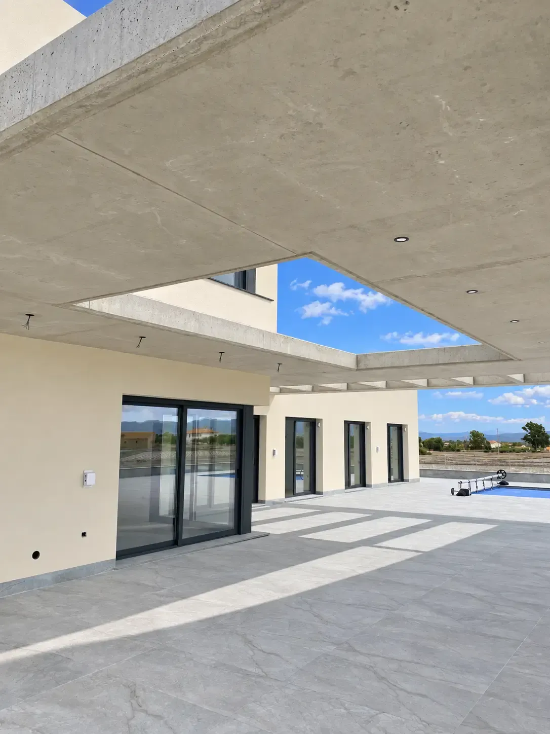 Amplia terraza moderna con puertas corredizas de vidrio, paredes de color beige