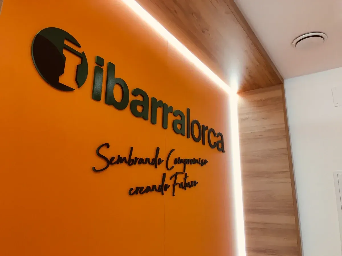 Pared naranja con logotipo y eslogan de Libarotca iluminados en un interior moderno.