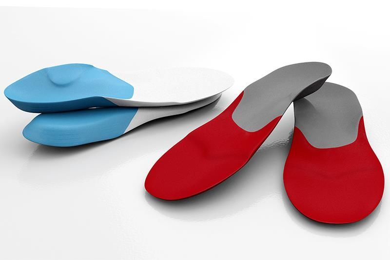 Ein Paar rote Einlegesohlen liegt neben einem Paar blauer Einlegesohlen
