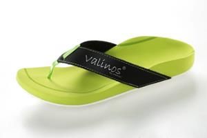 Ein Paar grüne Sandalen mit einem schwarzen Riemen mit der Aufschrift „Valinos“ darauf.