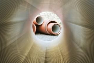 Ein Mann läuft auf einem Gehweg neben einem Kanaldeckel entlang.