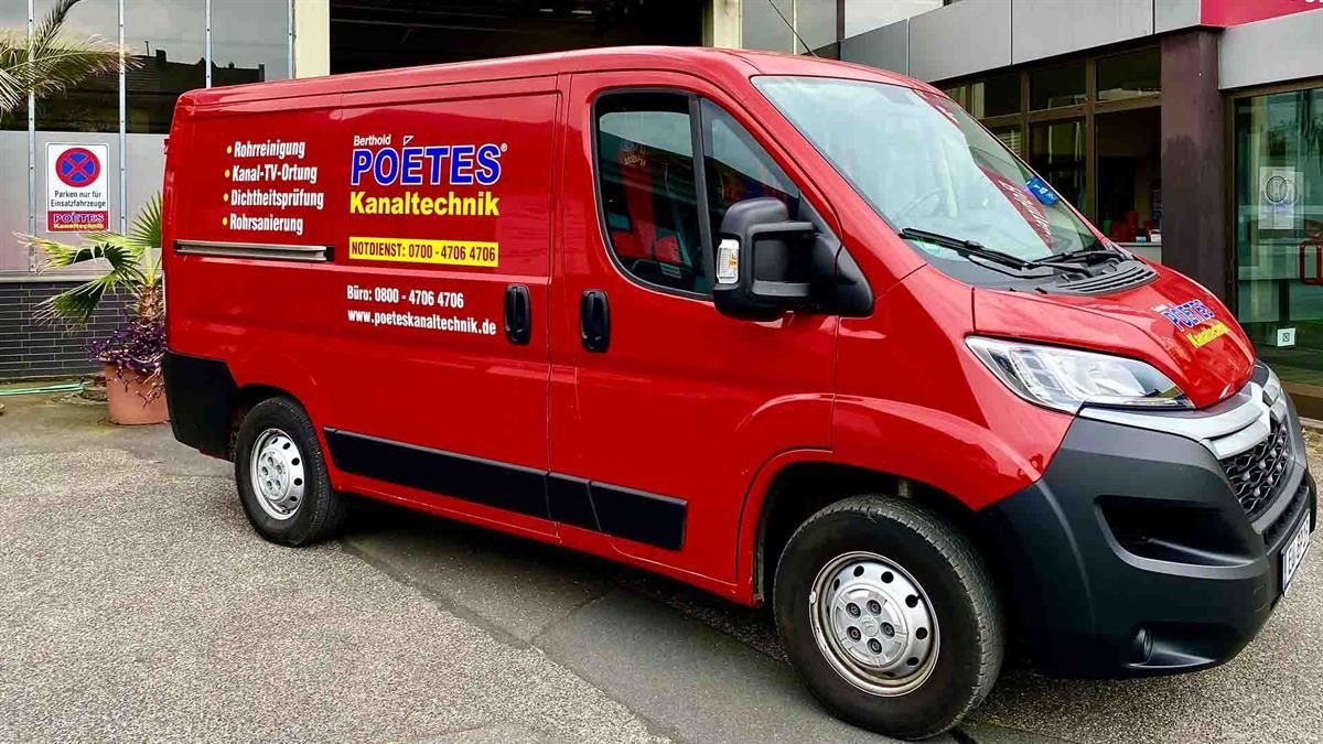 Ein roter Lieferwagen steht vor einem Gebäude.