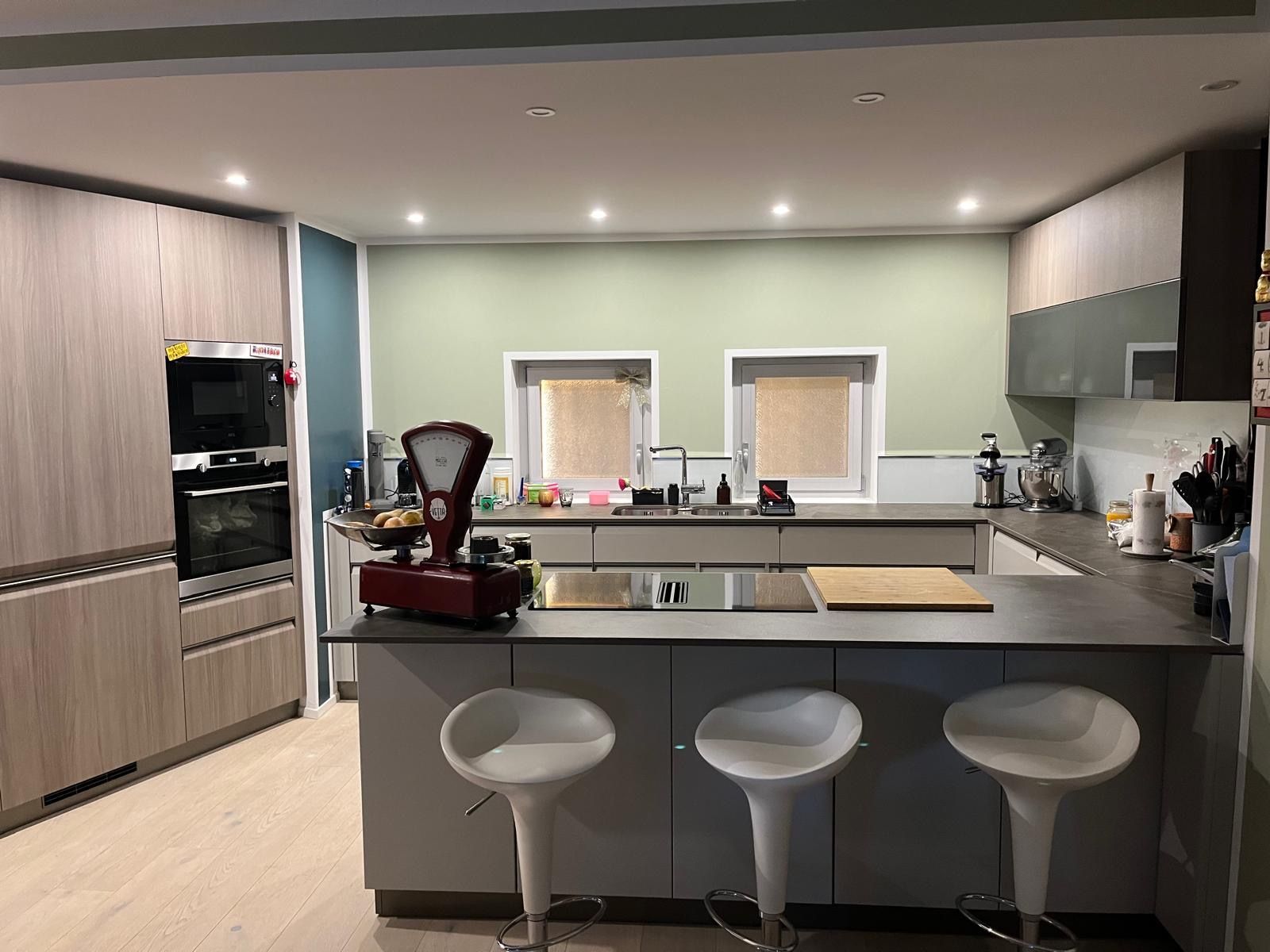 Una stanza vuota con una parete blu, un pavimento in legno chiaro e una tenda bianca.