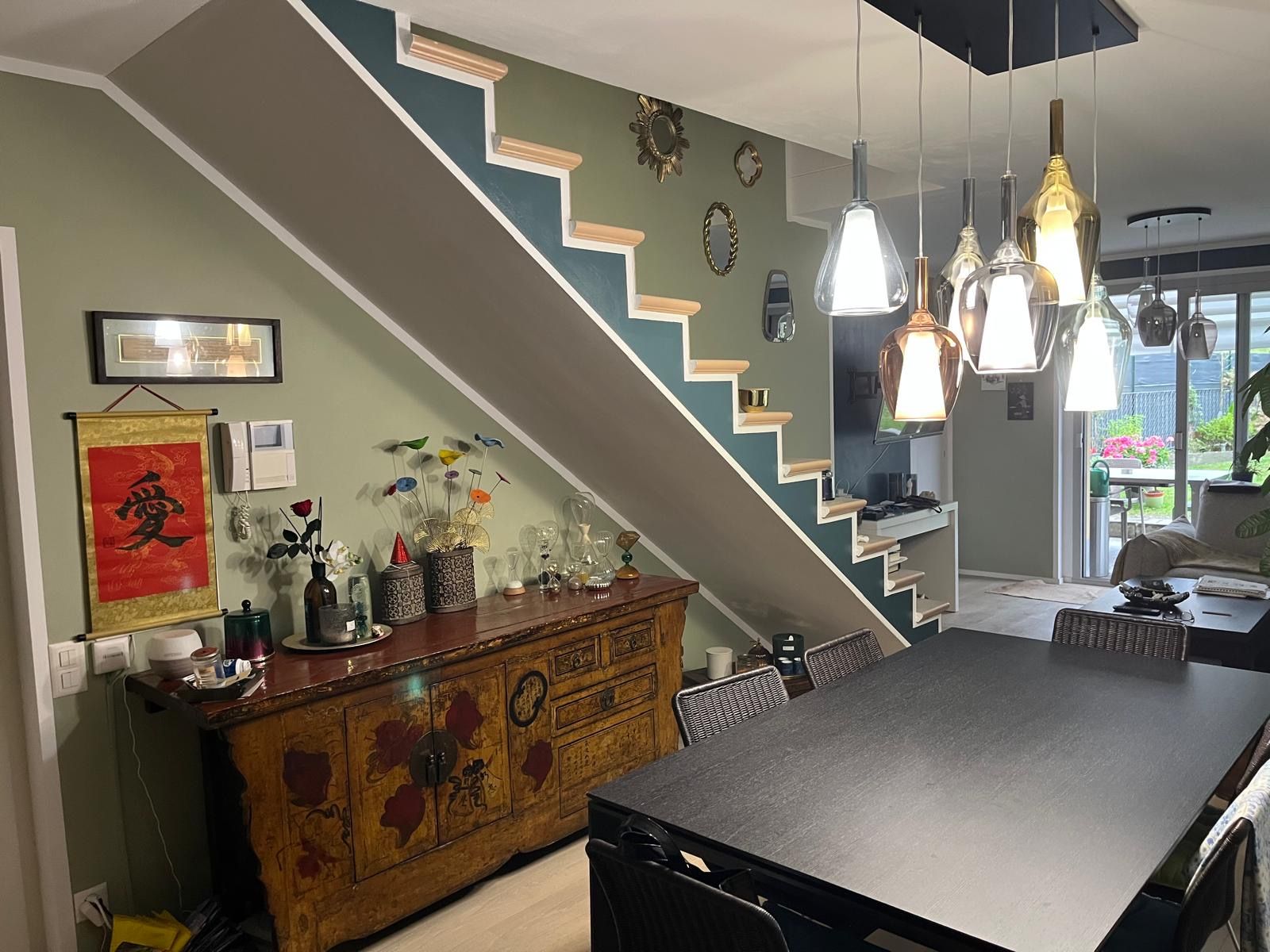 Stanza vuota con pareti blu-verdi, finiture bianche e pavimento in cemento.