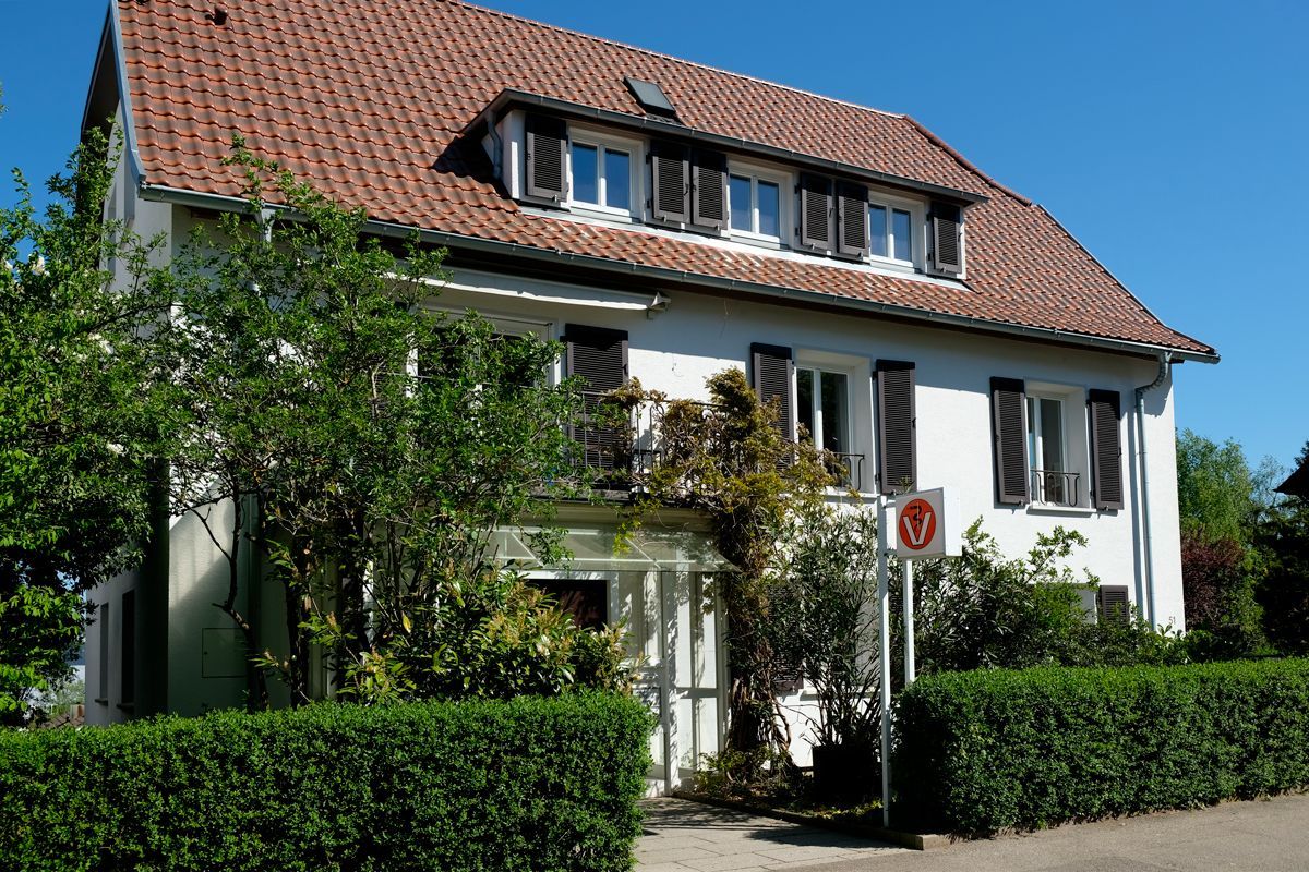 Tierärztin mit Klemmbrett hält Pfote von Hund, der von Frau gehalten wird, Kleintierpraxis Dr. Habel-Pöllmann