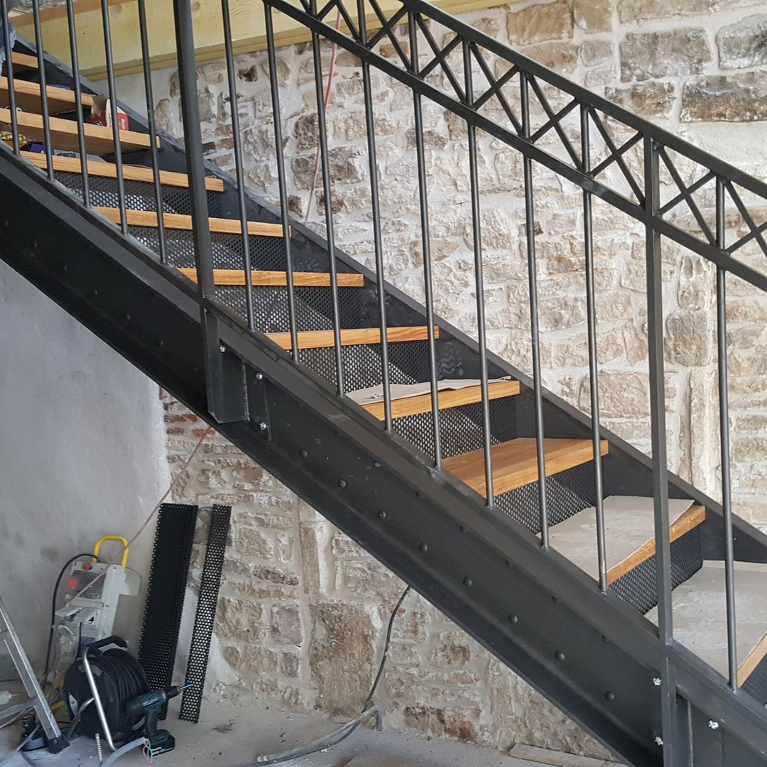 Un escalier avec une rambarde métallique et des marches en bois.