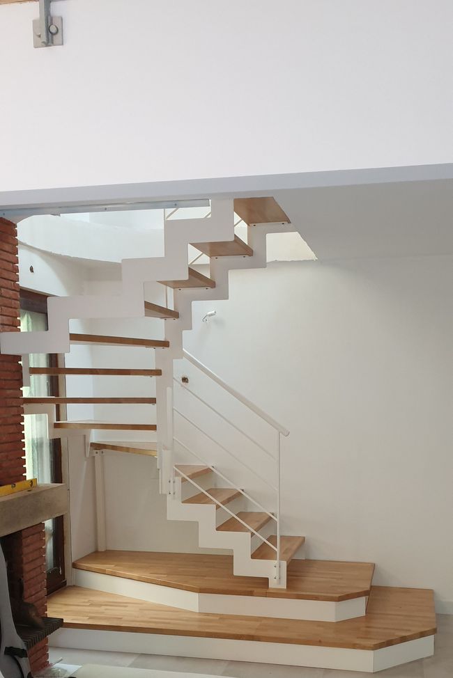 Escalier moderne suspendu avec marches en bois et limon central blanc.