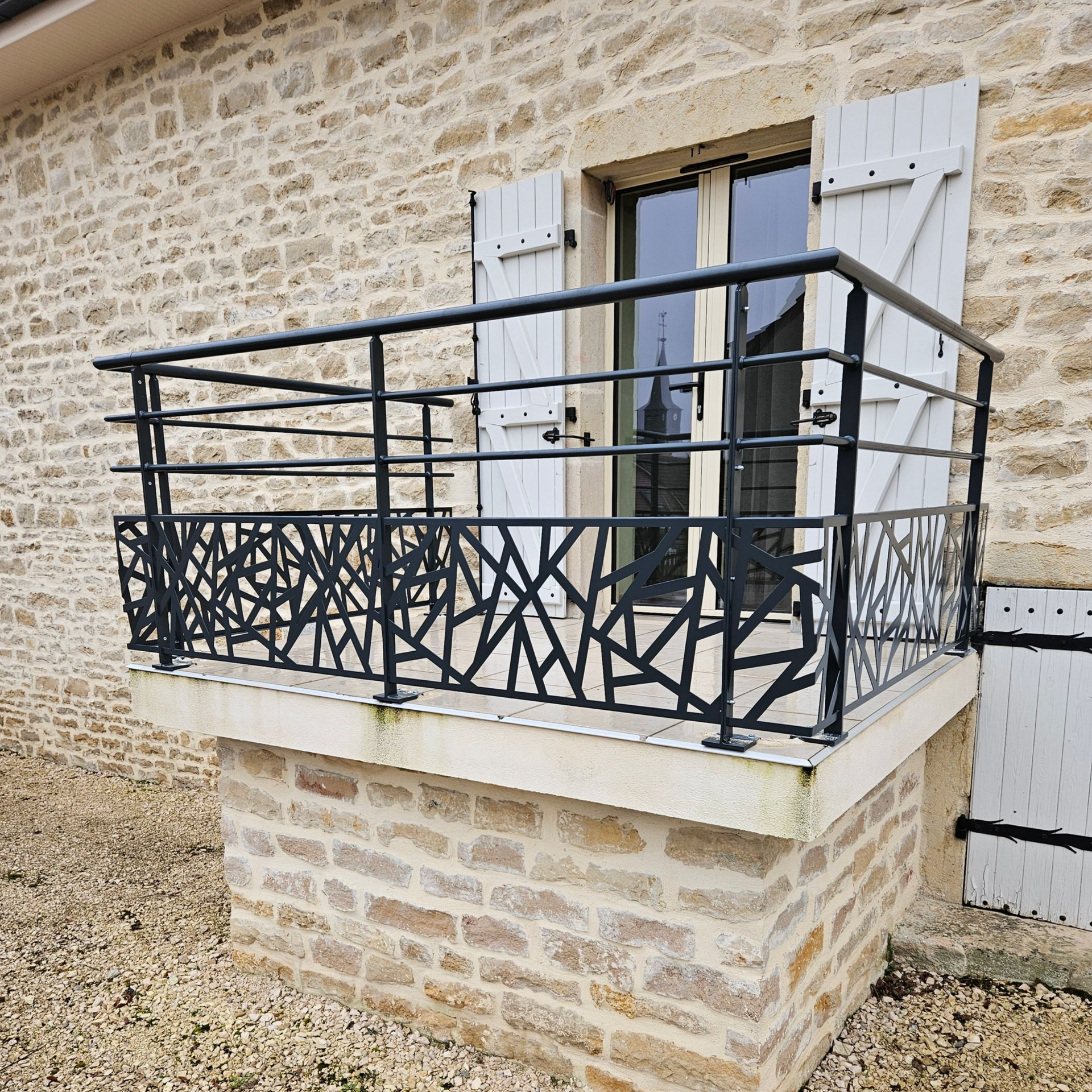 Balcon en pierre avec un garde-corps décoratif en métal.