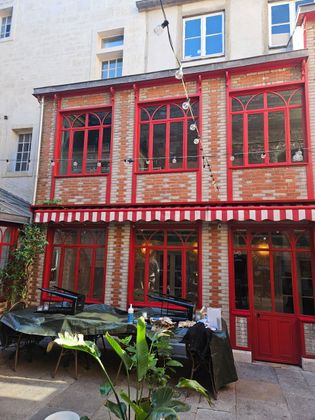 Bâtiment avec verrières rouges et murs en briques dans une cour extérieure.