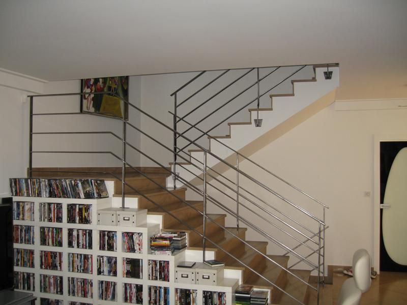 Escalier en bois avec garde-corps métallique dans un salon.