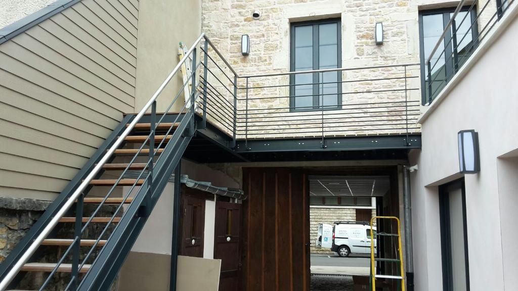 Aménagement extérieur avec escalier en acier et passerelle pour accès à l’étage.
