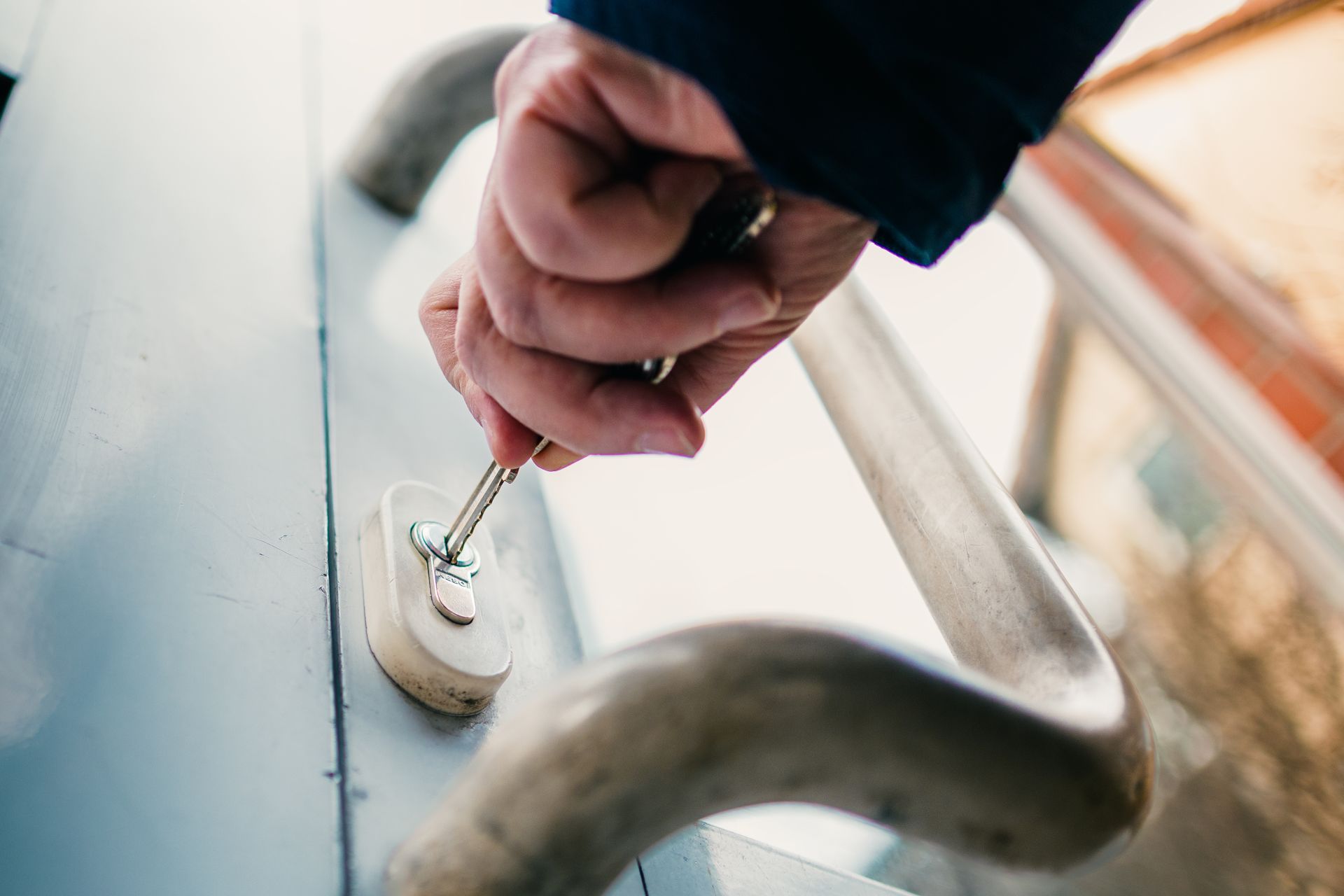 Main insérant une clé dans la serrure d'une porte métallique.