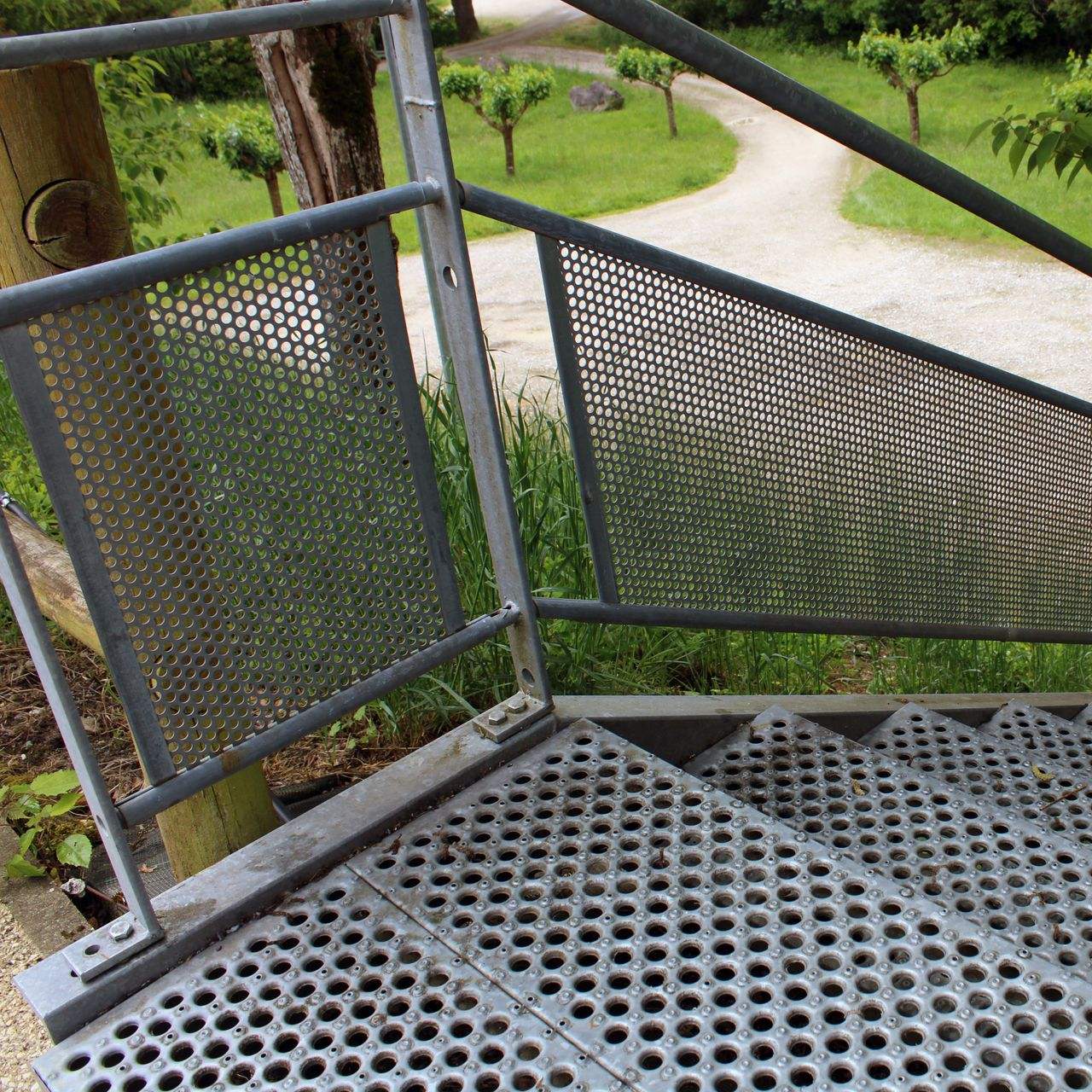 Accès extérieur en acier avec escalier industriel et protection latérale perforée.