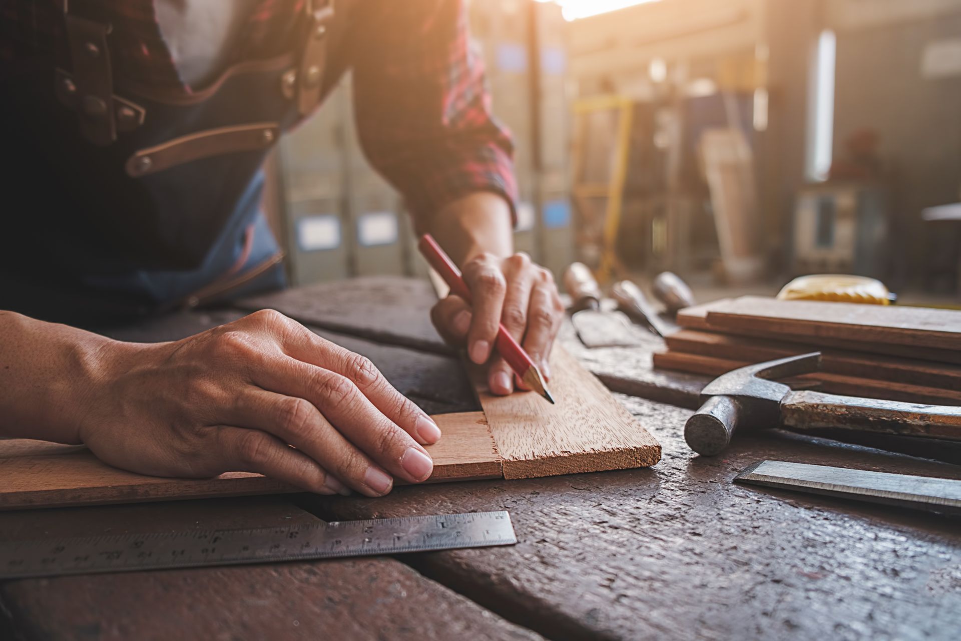 Artisan menuisier traçant une découpe sur une planche de bois.