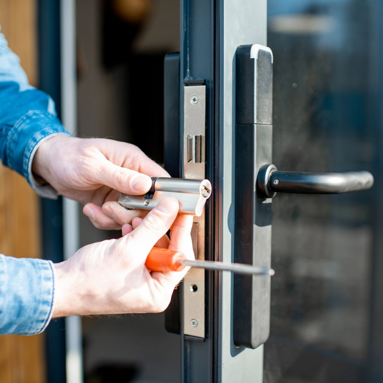 Technicien installant un cylindre de serrure sur une porte.