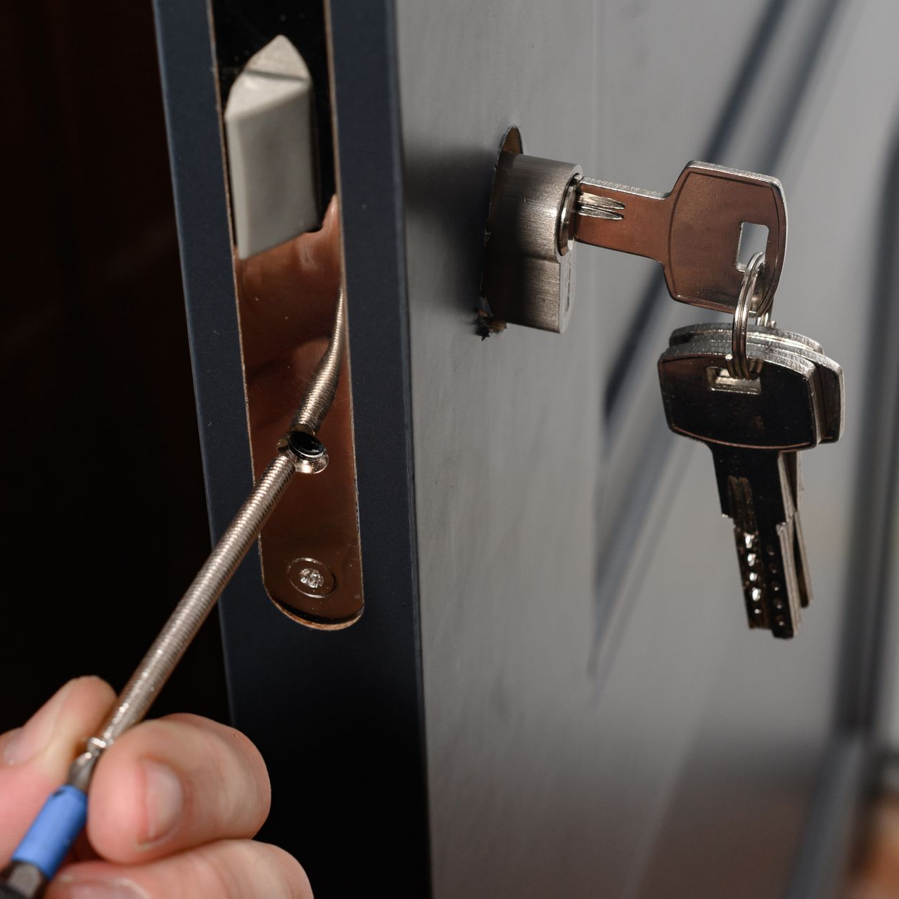 Réparation d’une serrure de porte à l'aide d'un tournevis.