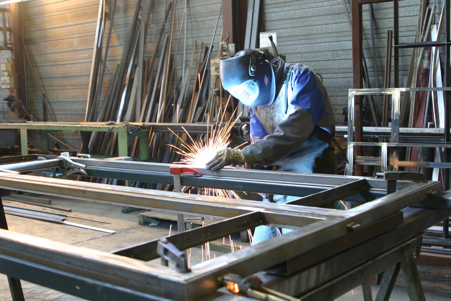 Un soudeur produit des étincelles sur une structure métallique dans un atelier.