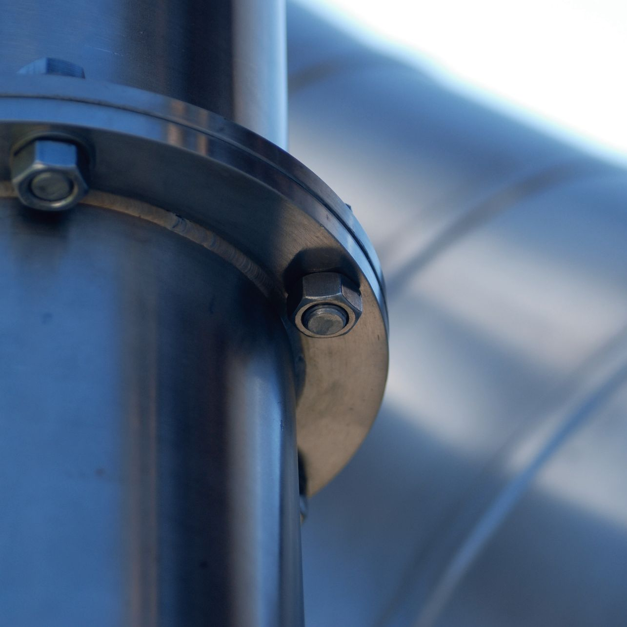 Gros plan sur une conduite industrielle en métal avec fixation boulonnée.