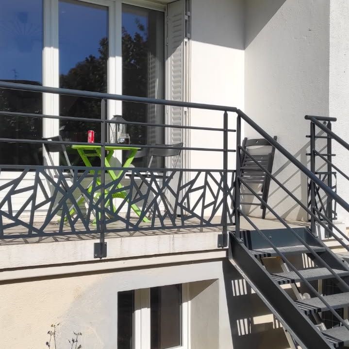 Balcon avec un garde-corps décoratif et escalier en métal.