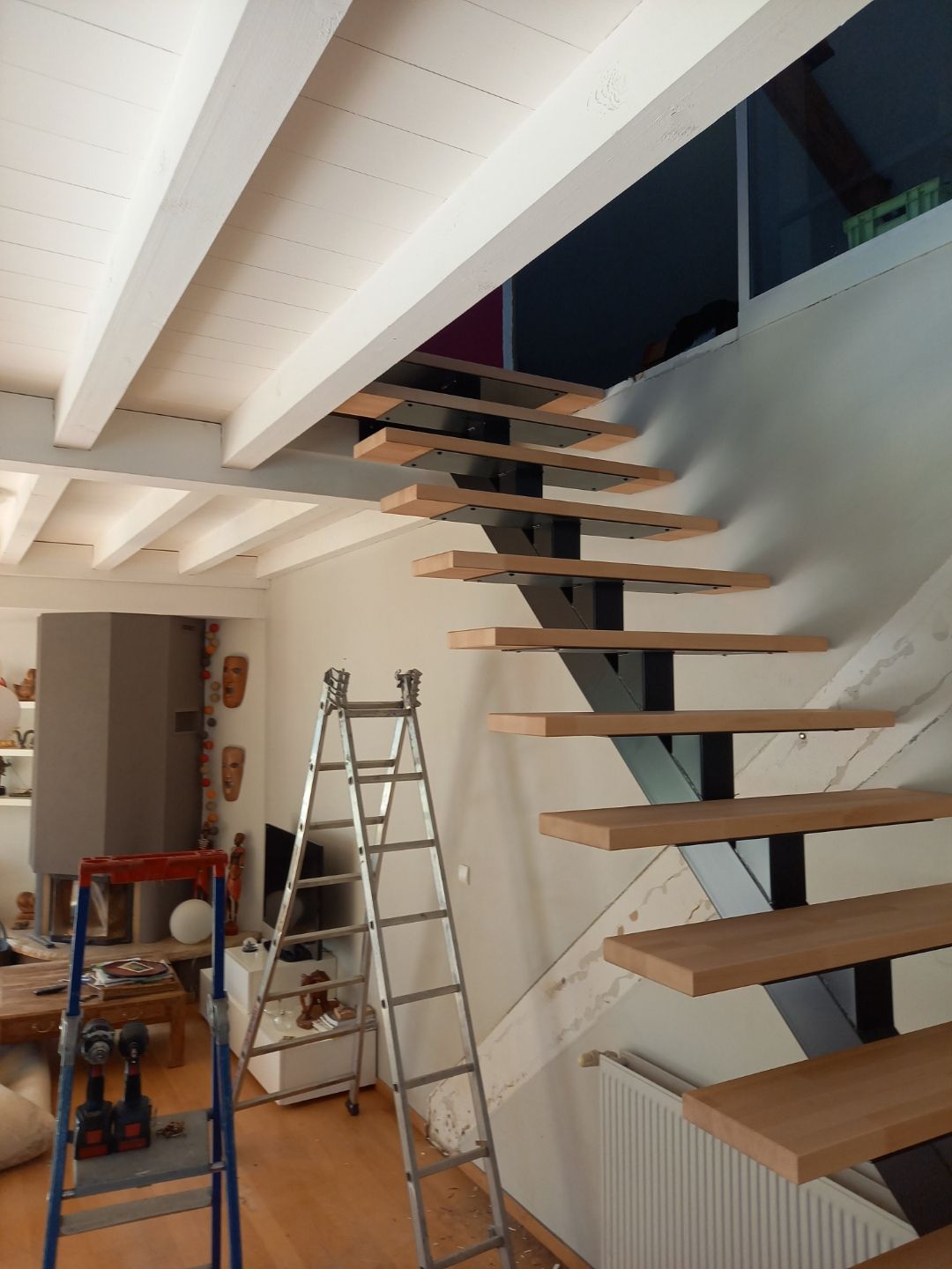 Installation d’un escalier suspendu en bois dans un intérieur en rénovation.
