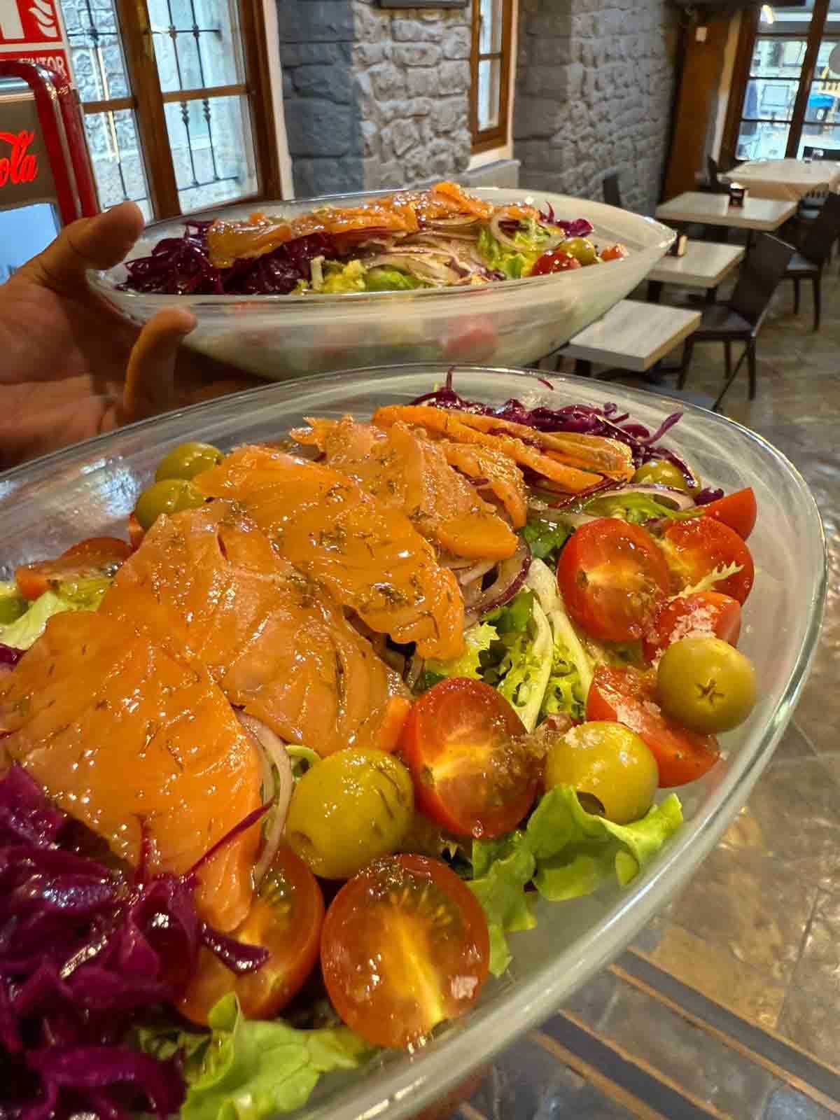 Una persona sostiene dos platos de ensalada en sus manos.