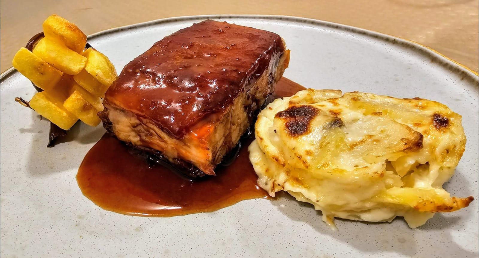 Un plato de comida con carne y patatas en una mesa.