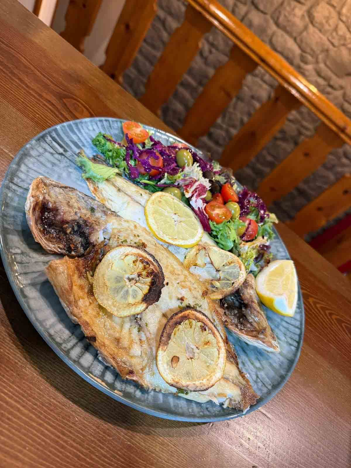 Un plato de comida con carne y verduras sobre una mesa de madera.