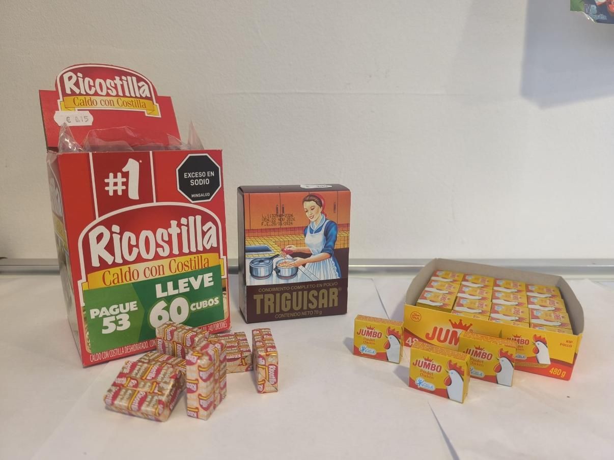 Surtido de cubitos de caldo en caja: Ricostilla, Trigisar y Jumbo, sobre superficie blanca.