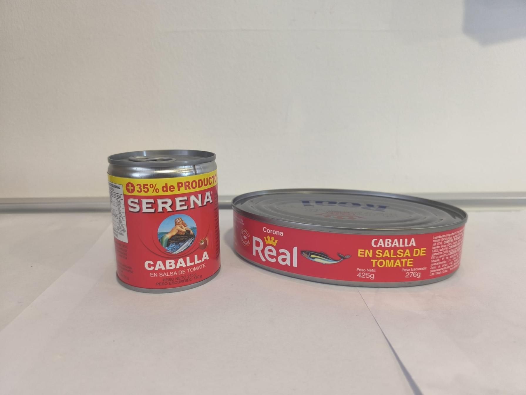 Dos latas de caballa en salsa de tomate. Una vertical, otra plana. Ambas con etiquetas rojas.