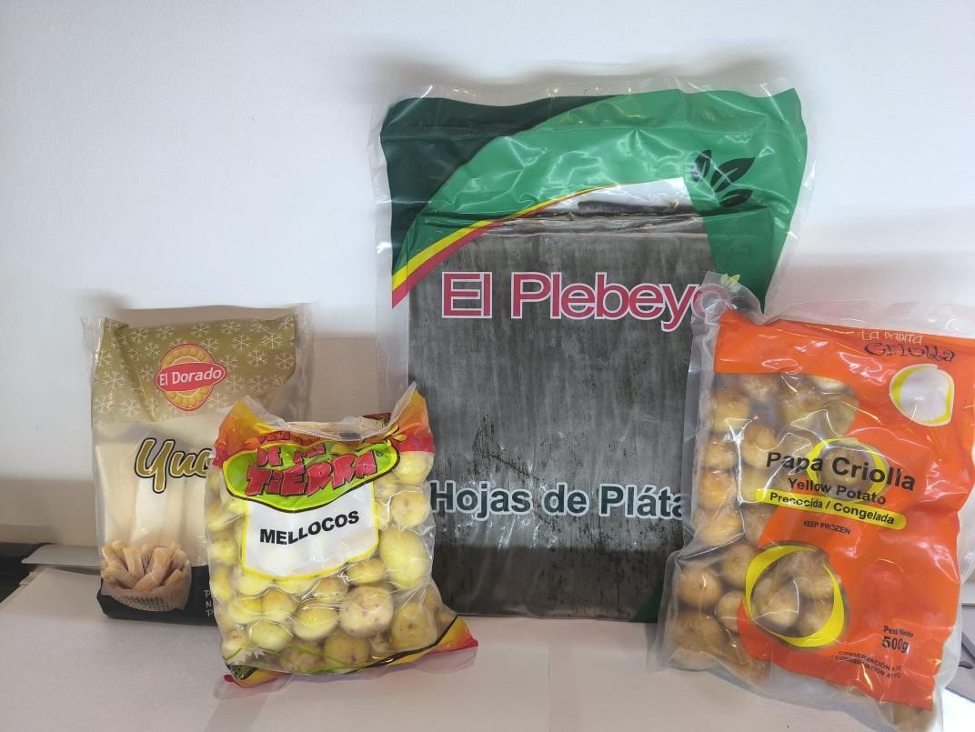Bolsas de comida: hojas de plátano, yuca y papas pequeñas. Varias marcas, colores y tamaños sobre una superficie blanca.