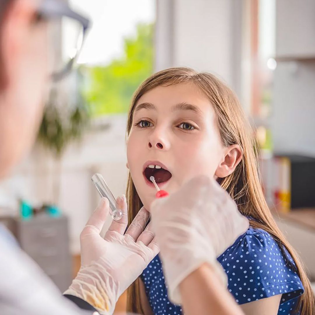 In una clinica luminosa, un dentista esamina la bocca aperta di un bambino con le mani guantate.