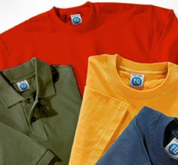 Una camiseta roja está encima de un polo verde y una camiseta amarilla.