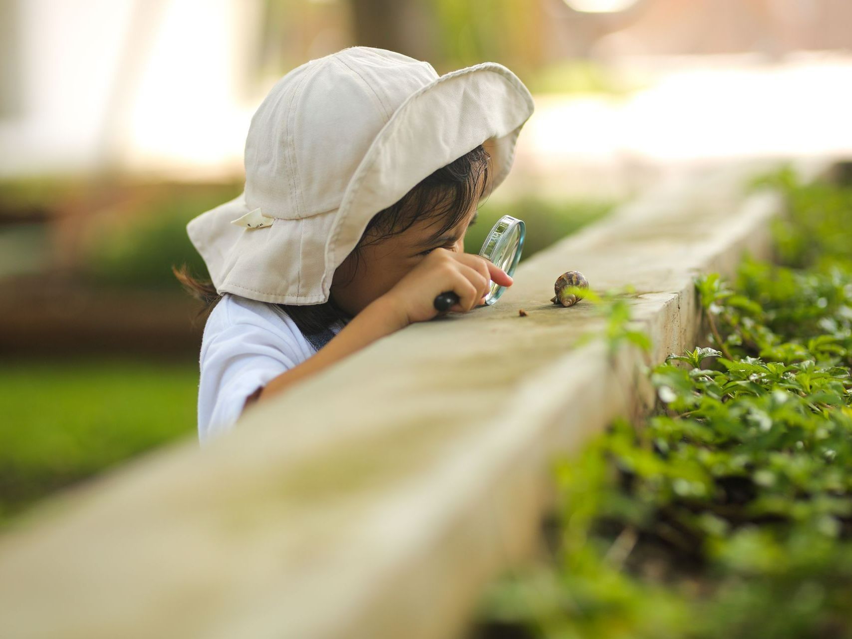 Enfant étudiant un escargot avec une loupe