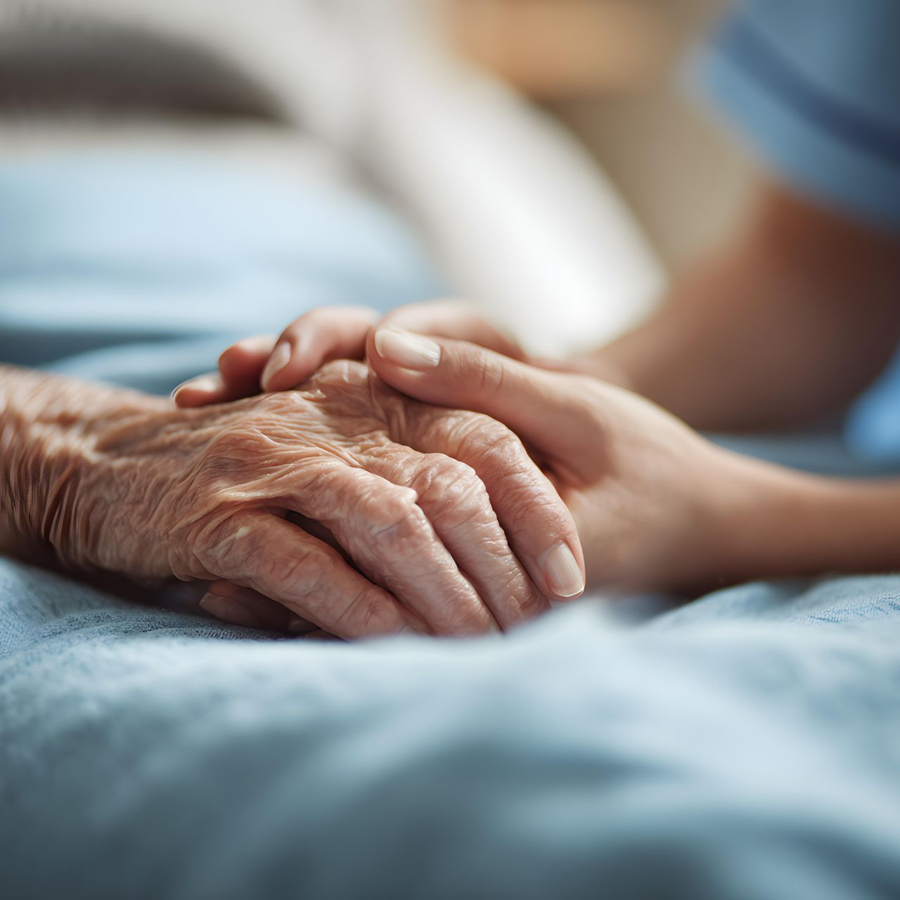 Mains jointes sur un lit bleu dans un geste attentionné et réconfortant