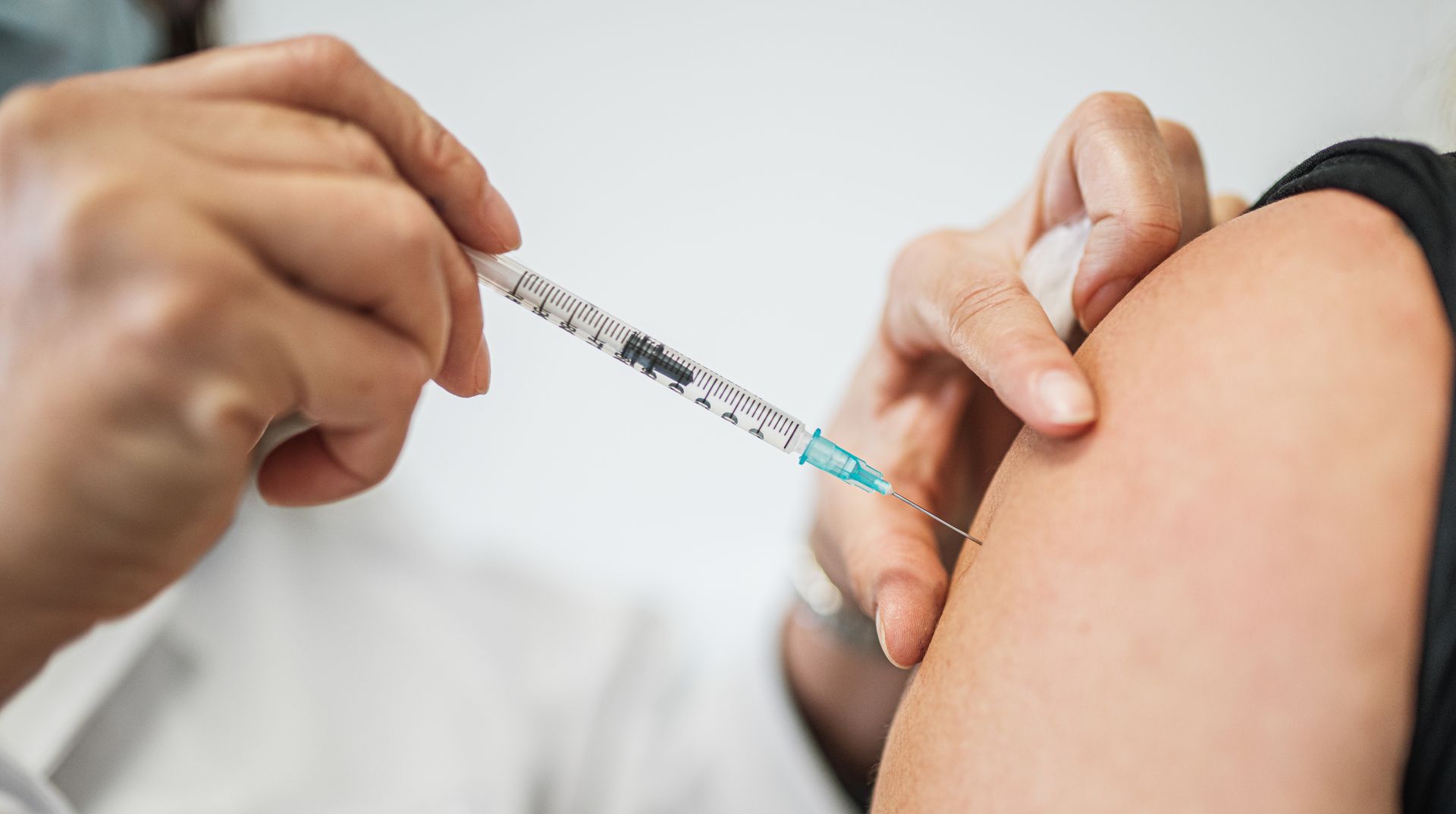 Un professionnel de santé injecte un vaccin dans le bras d'une personne à l'aide d'une seringue.