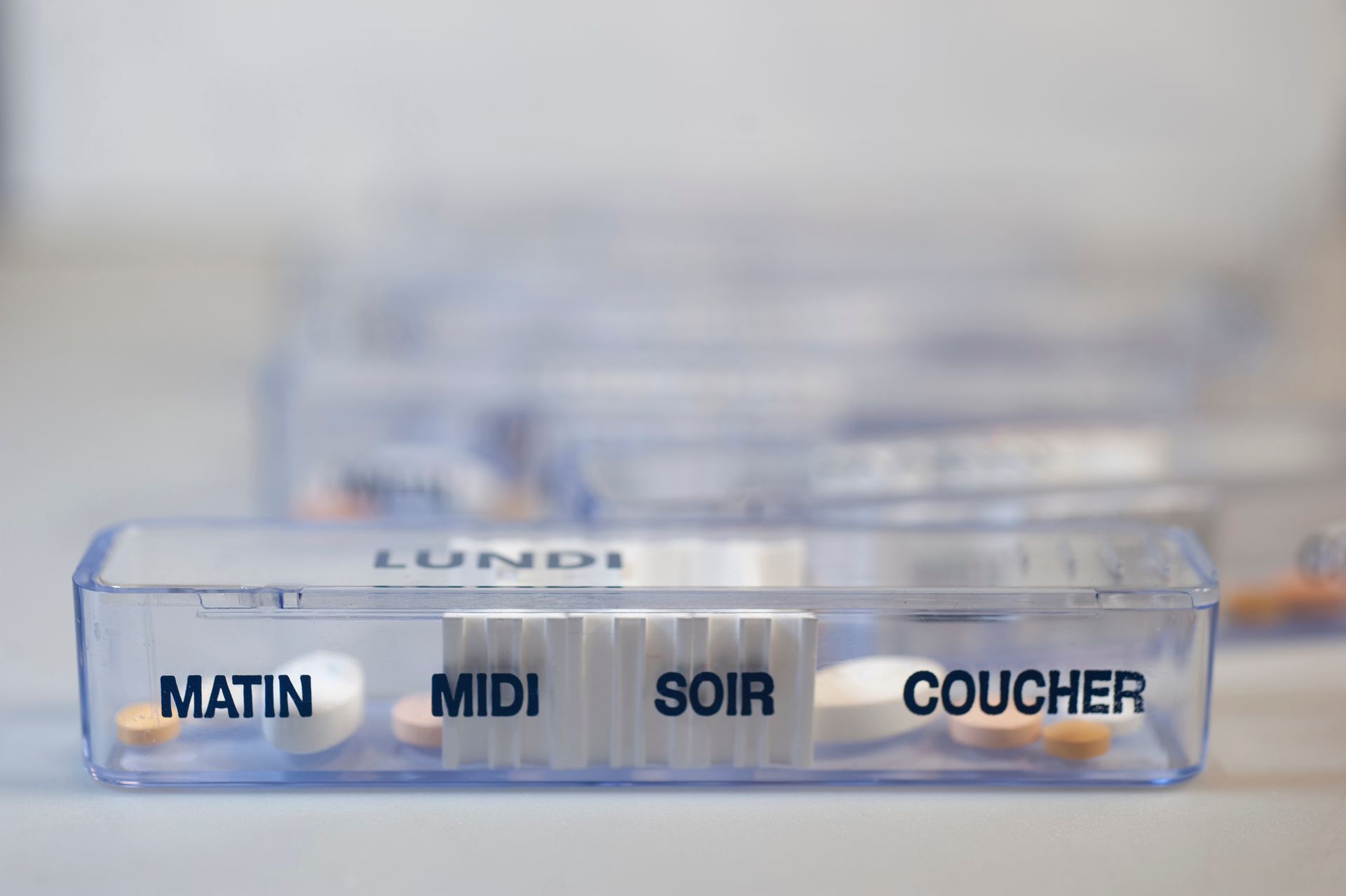 Pilulier transparent portant l'inscription LUNDI  et comportant des compartiments pour le matin, le midi, le soir et le coucher.
